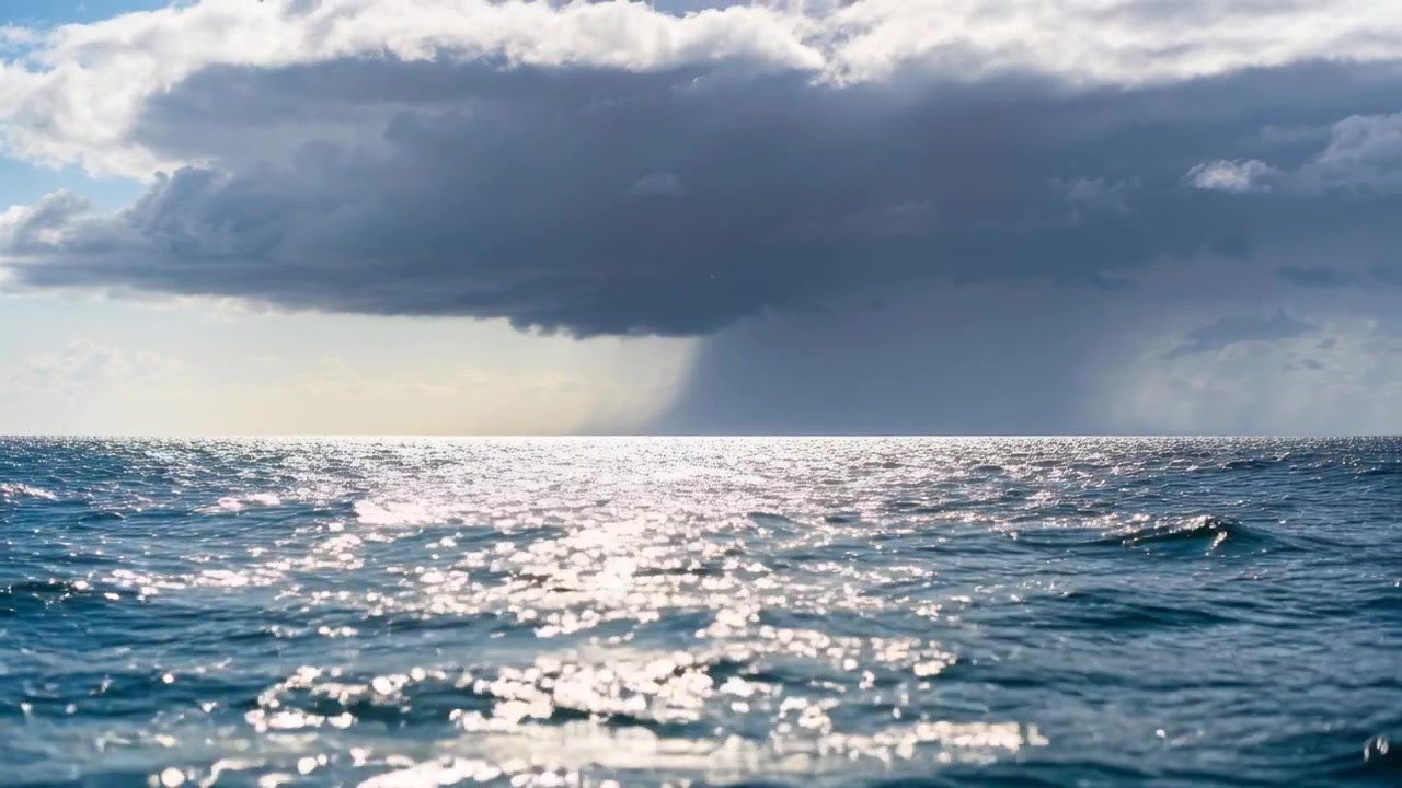Indrammer en mørk stormsky, der sender en fokuseret regnsøjle over et solbeskinnet hav, hvor sollyset glimter på bølgerne.