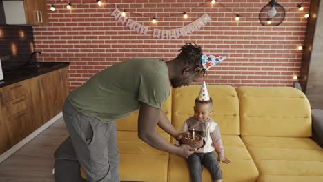 happy father gives birthday's cake for his son to blowing three candles