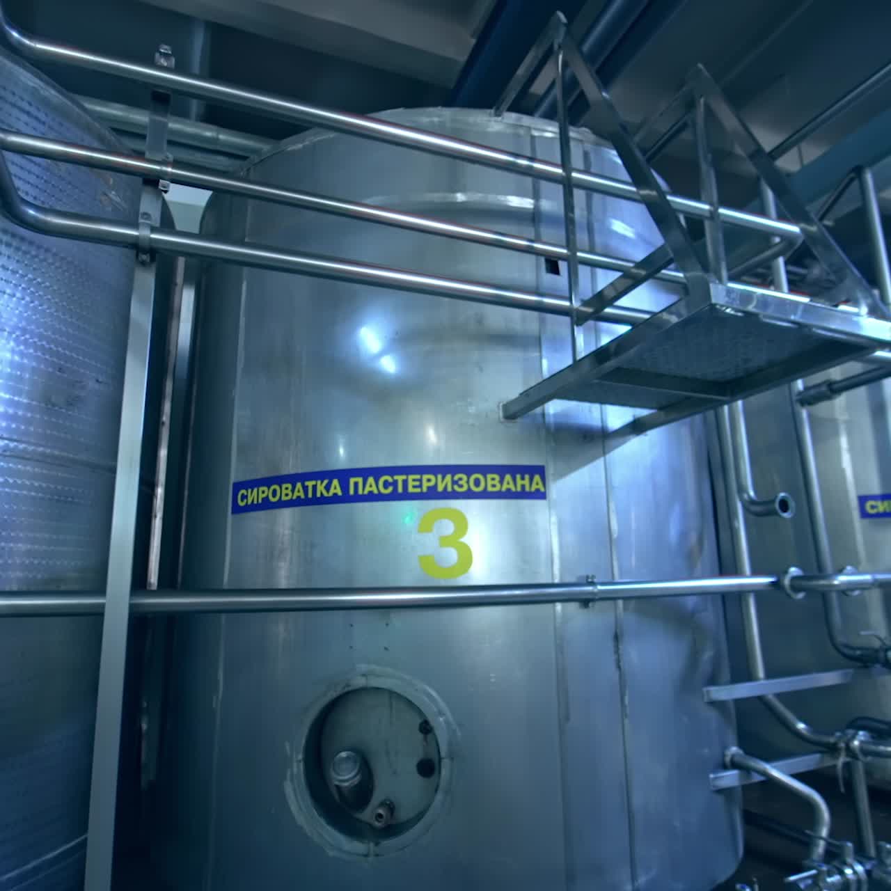 Huge steel reservoirs for storage and processing milk. Coming closer to the big metal tanks at milk factory