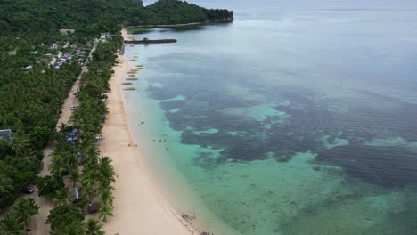 breathtaking, establishing overhead drone shot of crystal clear ocean bay with shallow reefs faced by white sand beaches and dense jungle of virac, catanduanes