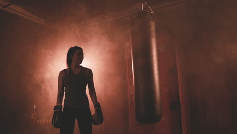 female boxer rests next to the punching bag