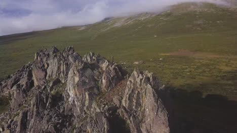 aerial view of a mountain range with rocky peaks and a grassy valley