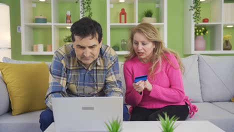 una pareja feliz y madura comprando en línea desde una computadora portátil.