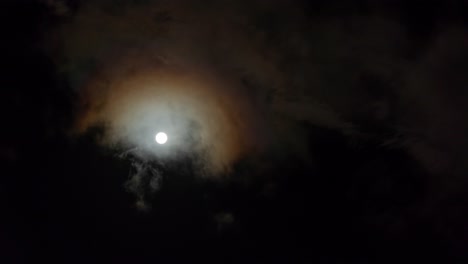 brillante luna llena brillante con nubes que pasan por delante, mirando hacia el cielo nocturno