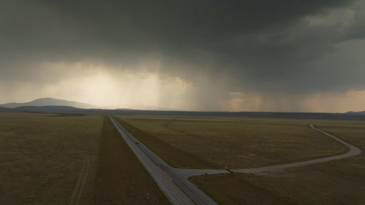 Dramatic skies loom over a vast Wyoming road, evoking solitude and wonder