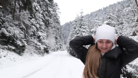woman wears a white warm hat on a frosty day looking at the camera on a background of winter forest woman wears a white warm hat on a frosty day looking at the camera on a background of winter forest happy woman relaxing in the mountains in winter