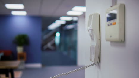 a person picks up a phone attached to the wall and then slams it down