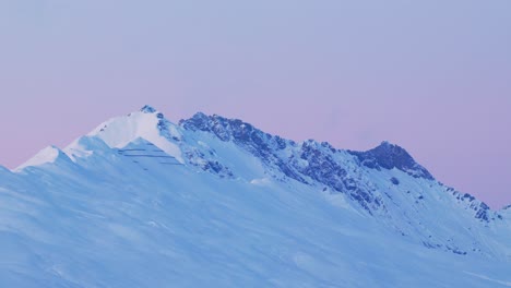 Witness-the-ethereal-charm-of-sunrise-over-a-snow-capped-mountain-range-silhouette-through-this-mesmerizing-drone-footage