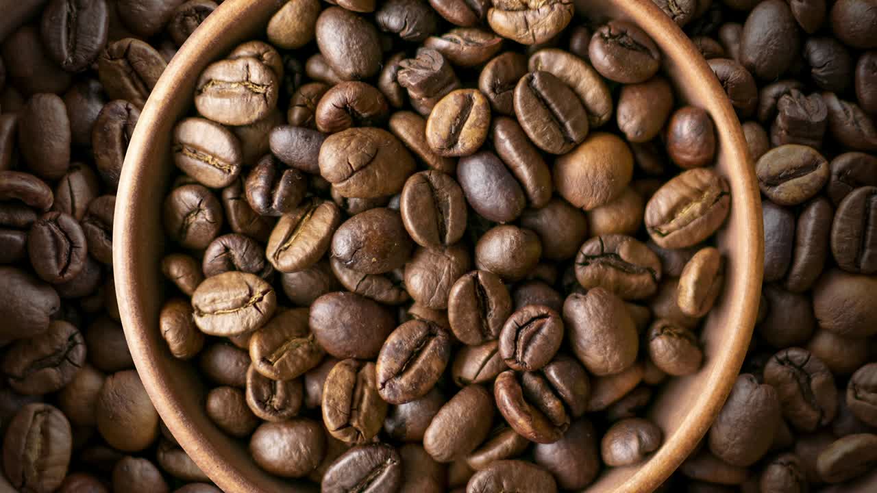 Chicchi di caffè tostati in una ciotola marrone ruotano. Sfondo animato a ciclo continuo con tema alimentare.
