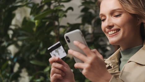 kaukasische studentin, die im freien mit dem smartphone online einkaufen.