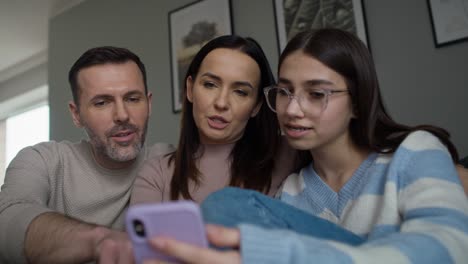familia caucásica divirtiéndose mientras navegan juntos por el teléfono móvil