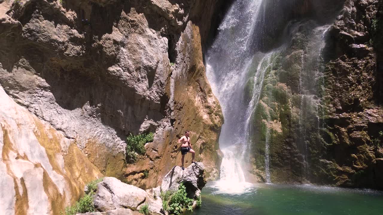 Man standing by waterfall in canyon