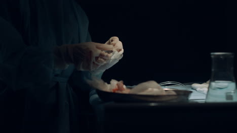 nurse hands preparing tools for wound suturing in dark operating room closeup.