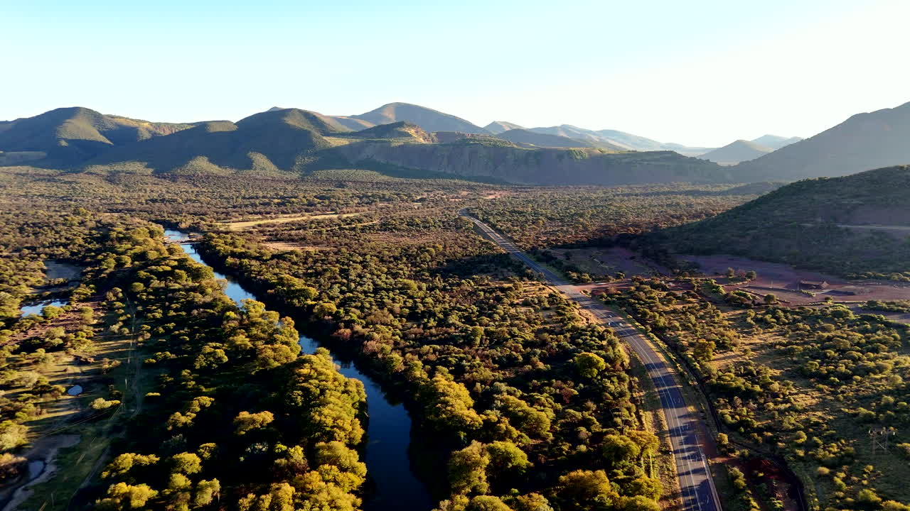 Aerial view over river next to main road and open pit mine in rural countryside
