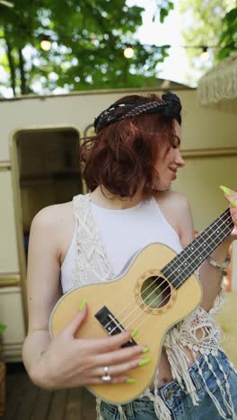 woman playing ukulele outdoors near campervan