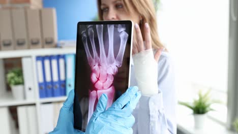 doctor shows patient x-ray of fractured wrist on tablet