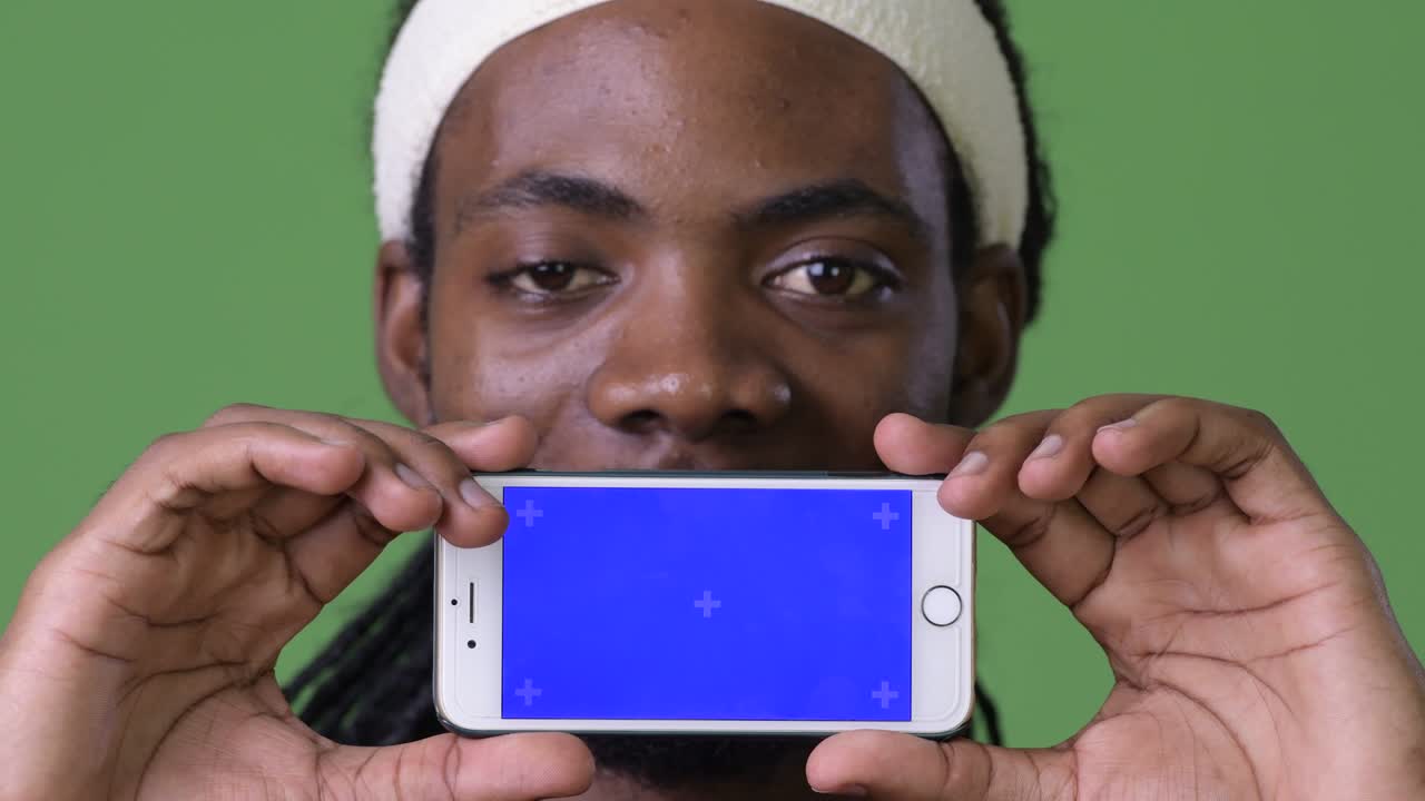 Young handsome African man with dreadlocks against green background