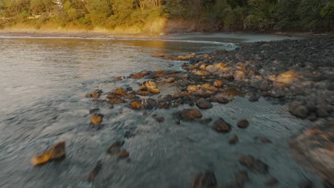 drone flying on rocky shoreline of tropical beach on sunset