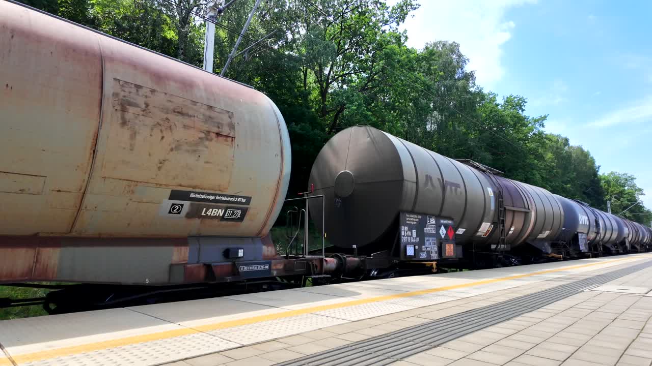 Long Freight Train with Tank Cars on a Railway Track at a Station