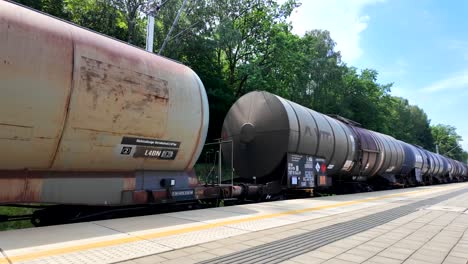 long freight train with tank cars on a railway track at a station