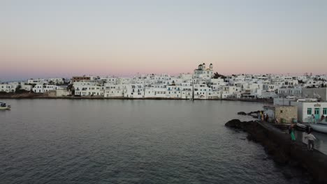 Paros,-Naoussa,-Greece-coastline-and-traditional-White-houses-during-sunset,-Aerial-view