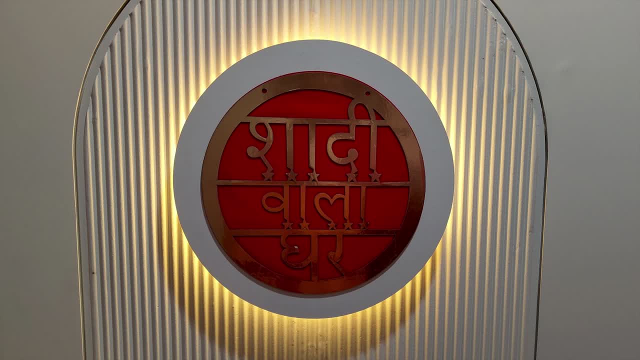 Stock footage of elegant wedding entrance decoration featuring Hindi text "Shaadi Wala Ghar" illuminated with warm golden lighting.
