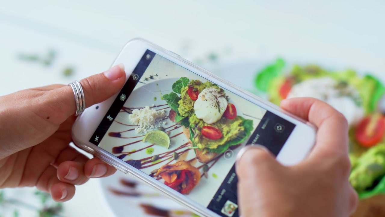 Person fotograferer avocadotoast med en smartphone