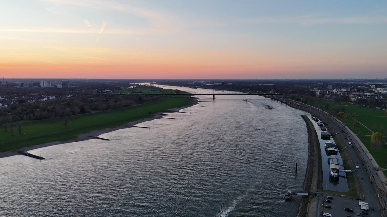 Drone glides over the Rhine in soft evening light with calm water and natural river mood.