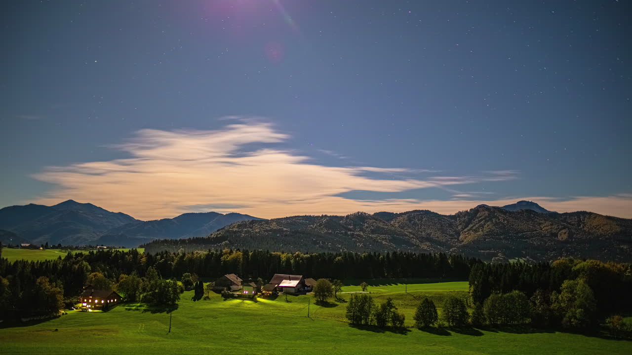 Nighttime time lapse with a bright moon and stars over Austria's countryside