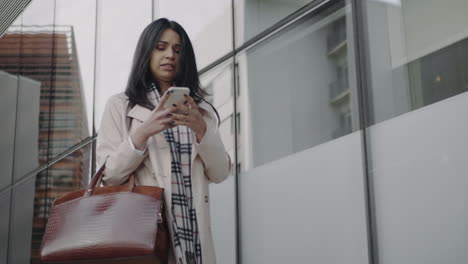 Frustrated-businesswoman-using-cellphone-outdoors.-Angry-woman-walking-on-street