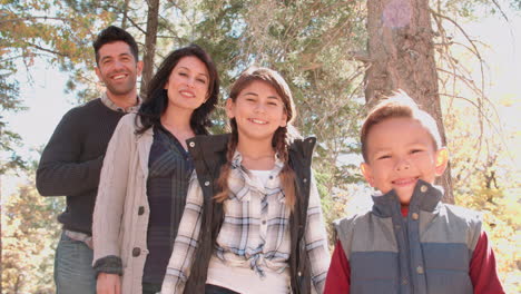 family standing, look to camera in a forest, handheld shot