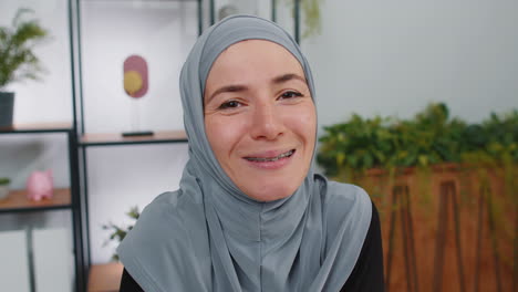 Retrato-De-Una-Joven-Empresaria-Musulmana-Tranquila-Y-Feliz-Con-Hijab,-Sonriendo-Amigablemente-Y-Quitándose-Las-Gafas