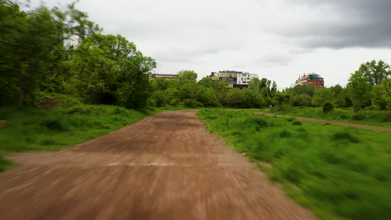 Ripresa aerea di una strada sterrata di ghiaia in città con dintorni verdi.