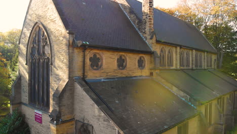 old british church in the light of sun at golden hour in middle of the forest in summer time cinematic drone footage