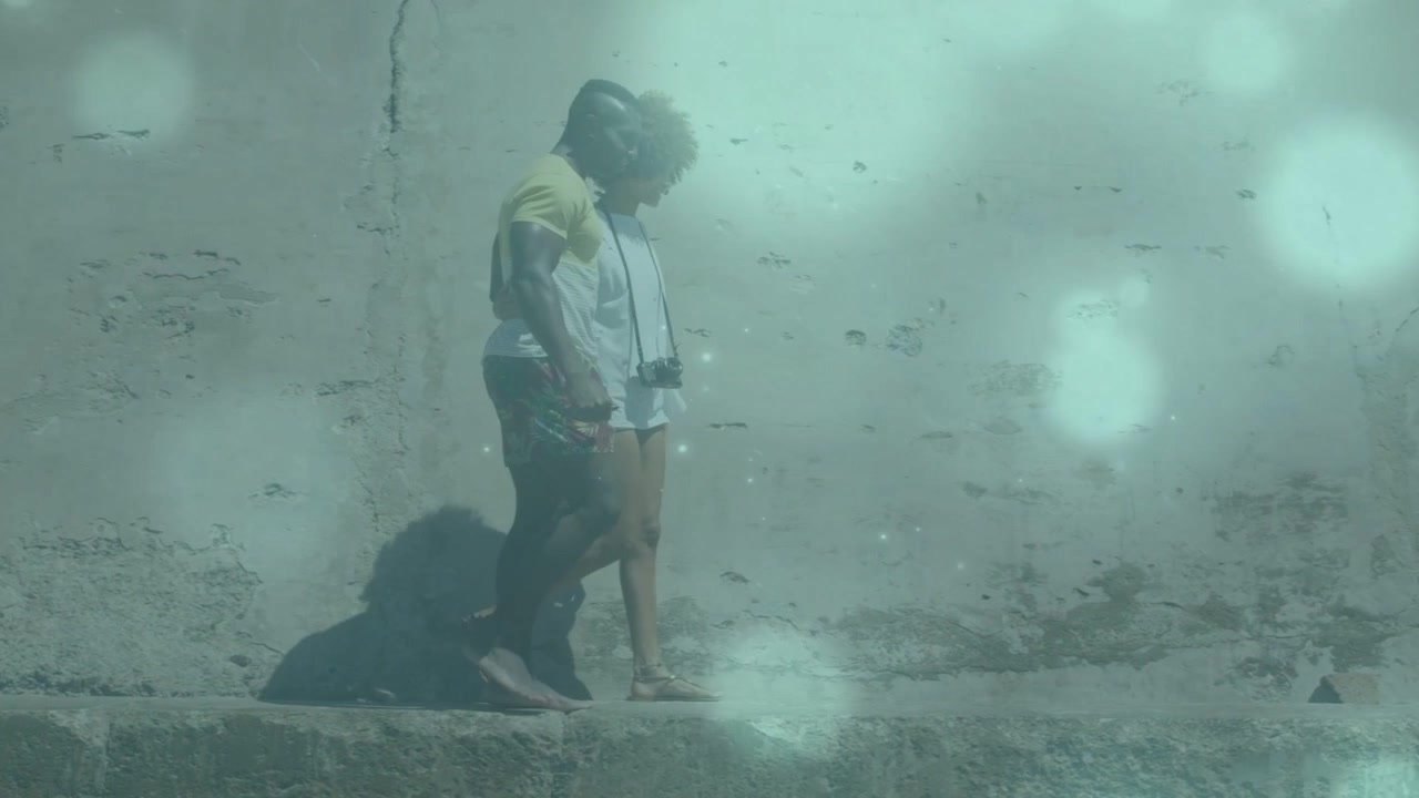 Fotografo di viaggi e donna che salgono su una sporgenza, stabilizzandosi per l'equilibrio mentre una foschia color verde acqua si diffonde sulla parete.