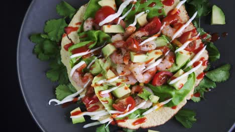 overhead of a freshly prepared flat open shrimp taco rotating on black background, 4k