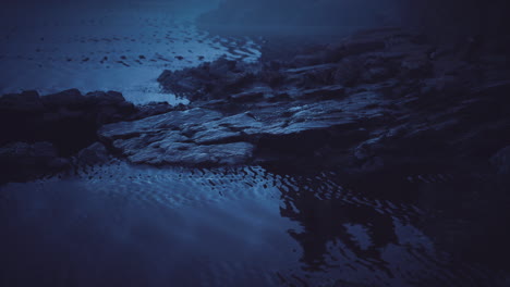 dark rock formations reflect in calm water during twilight hours