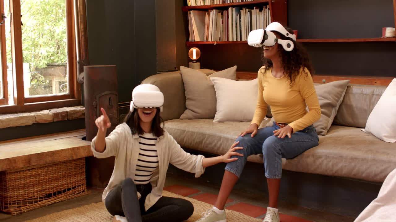 Multiracial female friends enjoying virtual reality experience at home, laughing and interacting