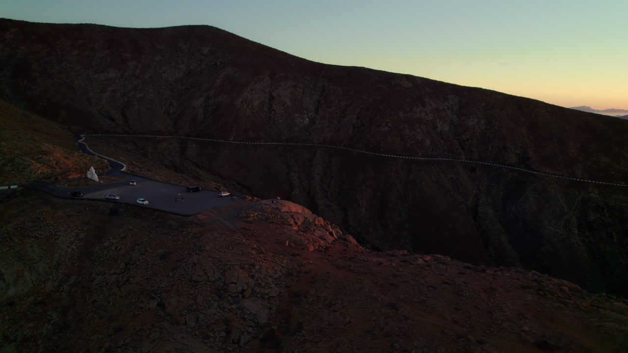 puesta de sol roja sobre un paisaje volcánico rocoso duro con cielo despejado con colinas empinadas