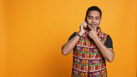 hombre feliz con ropa tradicional habla con un amigo de llamada, fondo de estudio