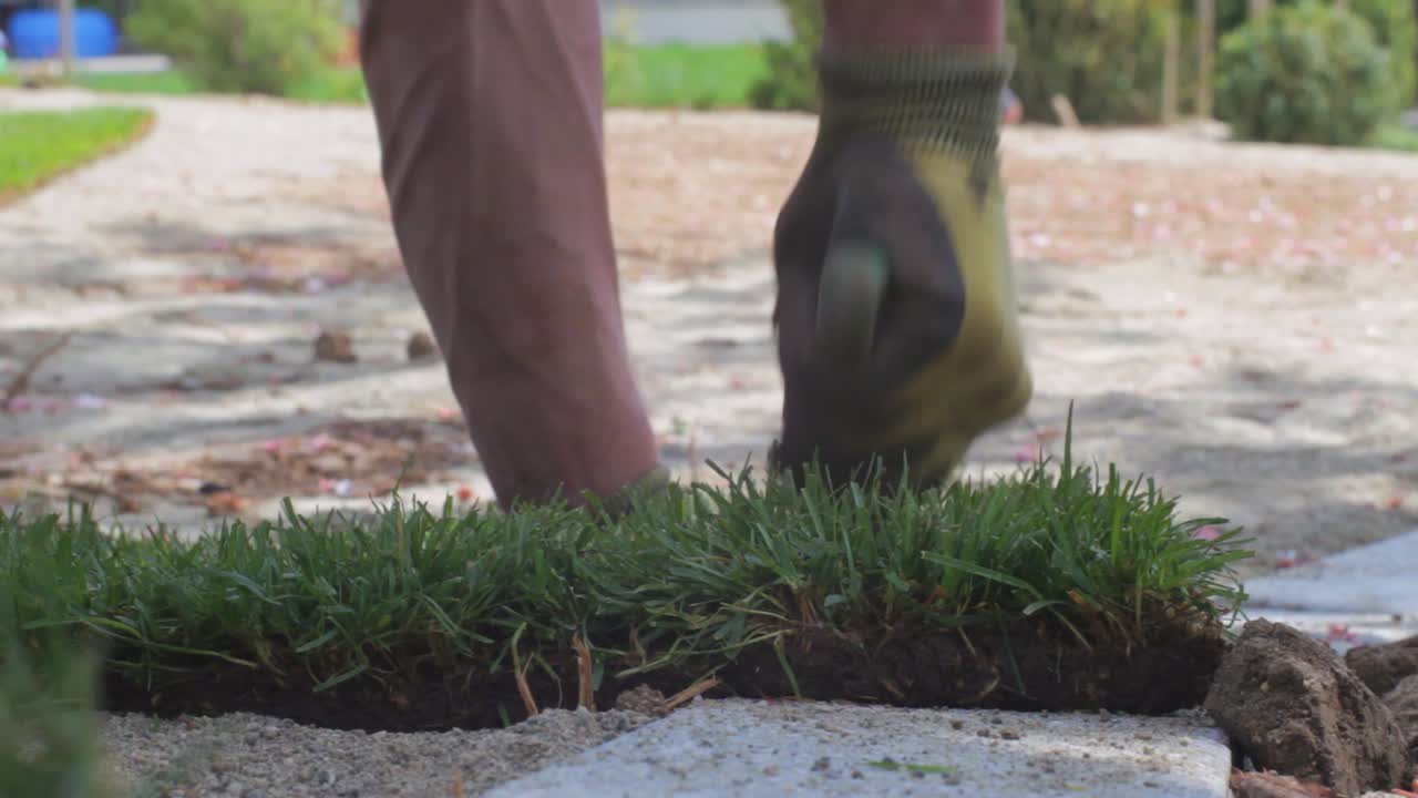 작업자가 펼쳐진 잔디를 준비된 영역에 맞도록 잘라냅니다.