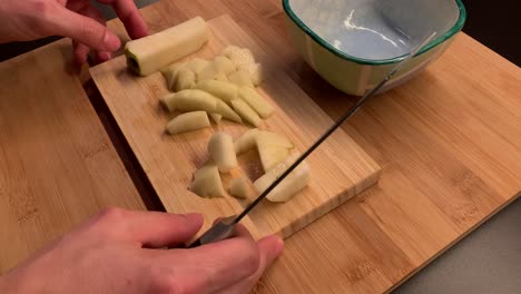 manos masculinas cortando una pera y poniéndola en un cuenco con un cuchillo