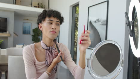 applying makeup, non binary person using mirror and phone at home