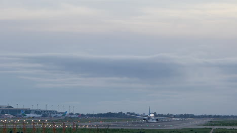 back telephoto view of standard commercial plane touching ground in landing lane