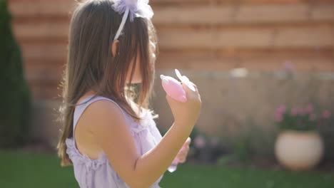 a little girl in a dress is blowing soap bubbles in the backyard on a sunny summer day