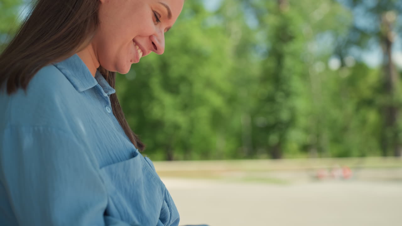 화창한 공원 벤치에 앉아 종이책을 읽는 여성, 공원 벤치에 앉아 페이퍼백 소설에 몰두하는 여성, 화창한 공원 벤치에 평화롭게 앉아 부드러운 미소를 지으며 페이퍼백 책을 읽는 여성