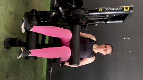 beautiful woman using chair flexor equipment at the gym