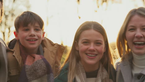 portrait of family on walk through autumn countryside together against flaring evening sun - shot in slow motion