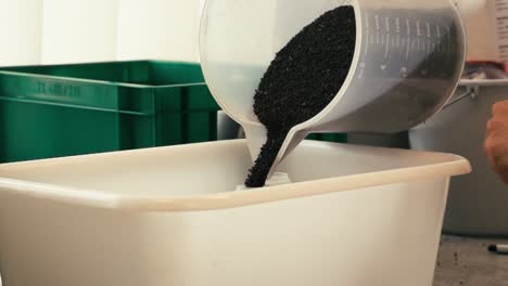 ripe canola gets poured into a white tank in slow motion in a laboratory