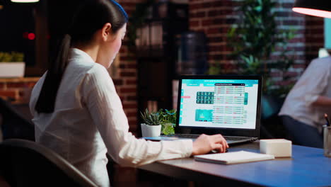 worker looking over statistical data financial graphs on laptop screen